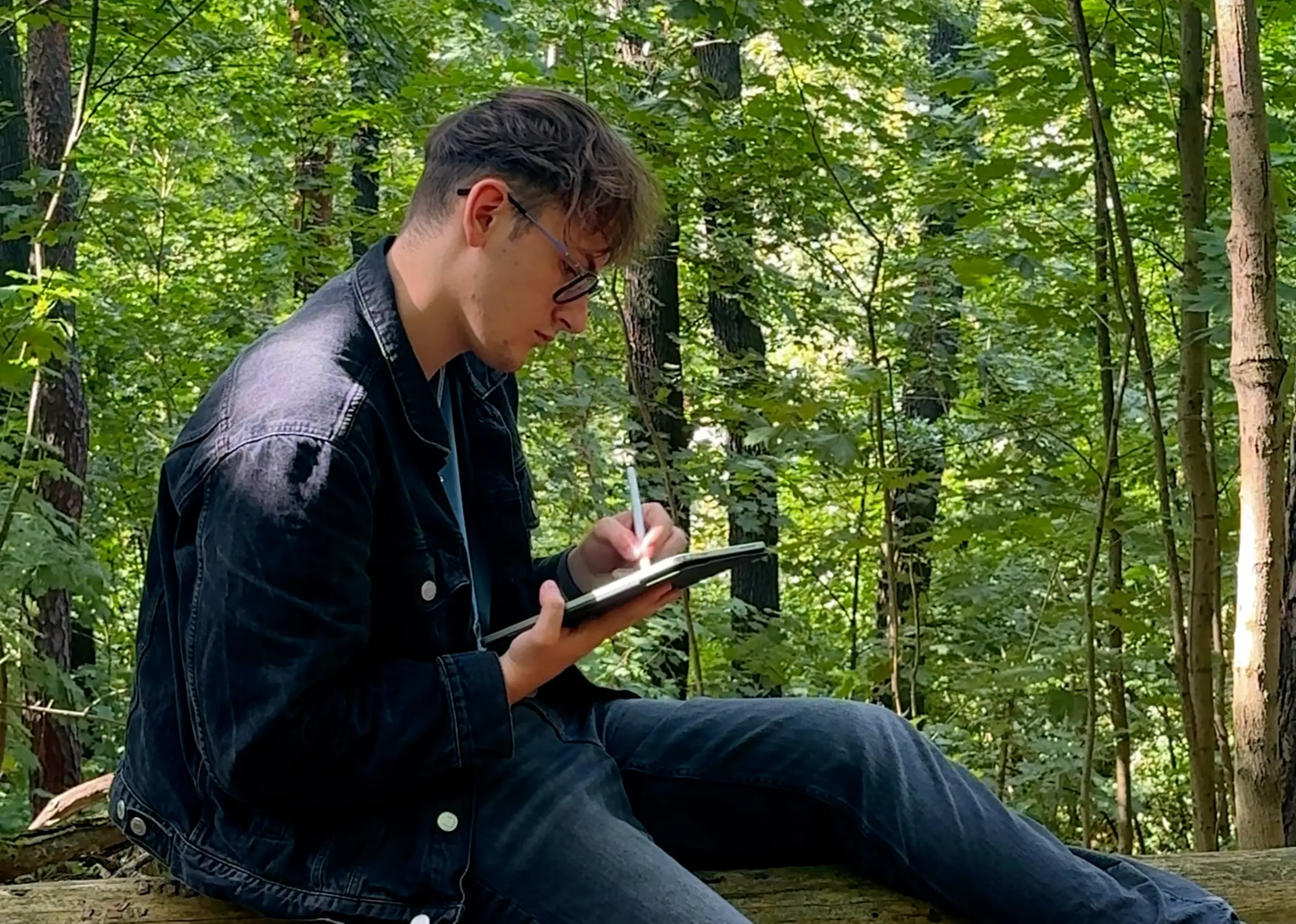 Ben zeichnet Entwürfe am Tablet in der Natur